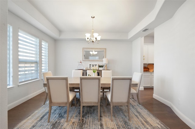 dining room with a raised ceiling, visible vents, a notable chandelier, and dark wood-style flooring