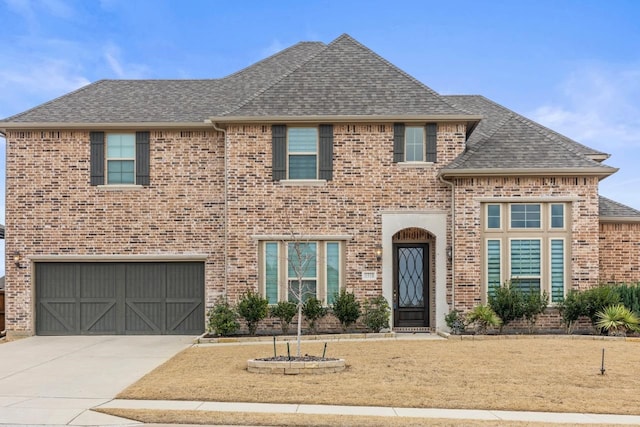 view of front of property featuring driveway, a shingled roof, a garage, and brick siding