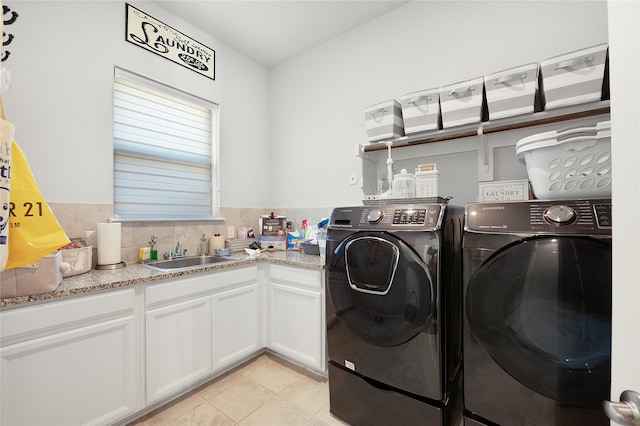 washroom featuring light tile patterned floors, washing machine and clothes dryer, a sink, and cabinet space