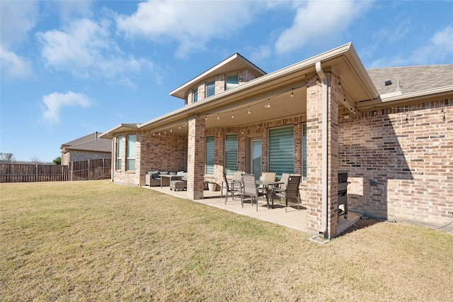 back of house featuring a lawn, a patio, fence, an outdoor living space, and brick siding