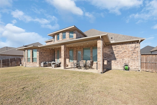 back of property with brick siding, a lawn, a fenced backyard, and an outdoor hangout area