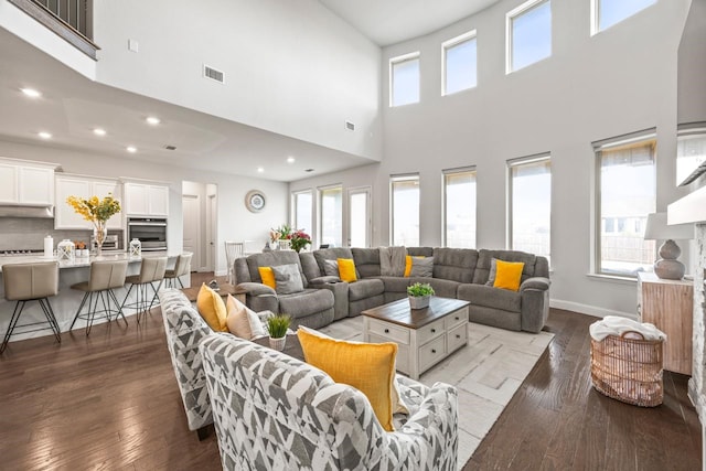 living area featuring hardwood / wood-style flooring, visible vents, and baseboards