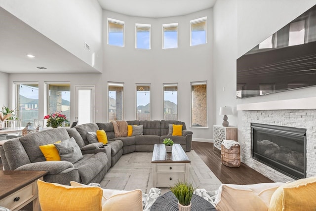 living room with visible vents, a fireplace, baseboards, and wood finished floors