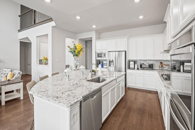 kitchen featuring appliances with stainless steel finishes, an island with sink, a sink, and white cabinetry