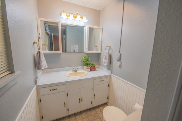 bathroom featuring vanity, a textured ceiling, and toilet