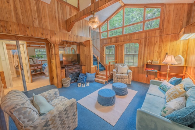 living room with carpet flooring, high vaulted ceiling, and wooden walls