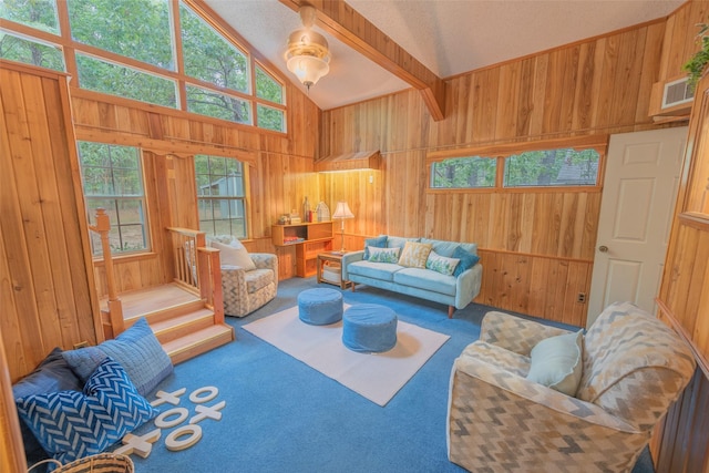 carpeted living room with beam ceiling, high vaulted ceiling, and wooden walls