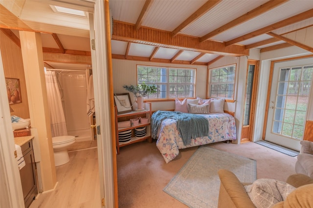 bedroom featuring lofted ceiling with beams, wooden walls, and multiple windows