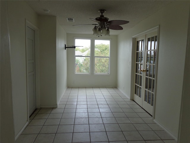 tiled empty room featuring french doors and ceiling fan