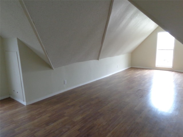 bonus room with dark hardwood / wood-style flooring and lofted ceiling