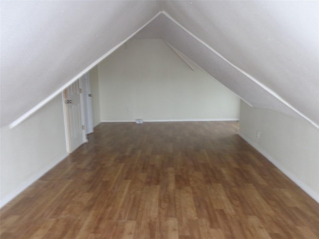 additional living space with dark hardwood / wood-style flooring and vaulted ceiling