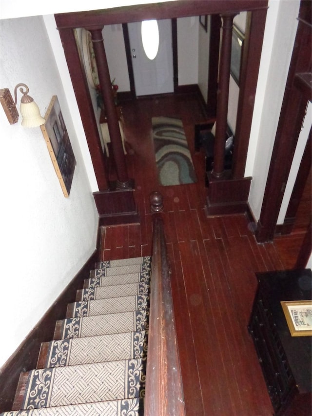 stairs with wood-type flooring and ornate columns