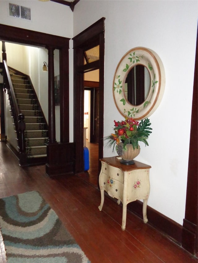 foyer featuring decorative columns and dark wood-type flooring