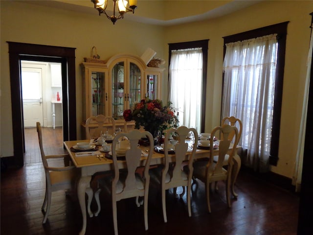 dining room featuring a notable chandelier, dark wood-type flooring, and a wealth of natural light