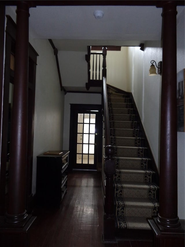 staircase featuring ornate columns and wood-type flooring