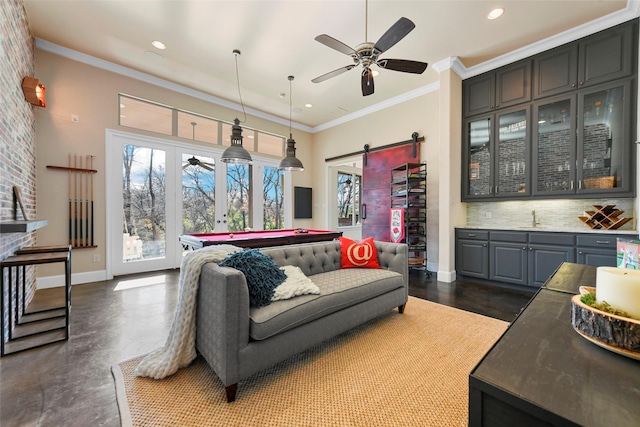 living room featuring billiards, ornamental molding, a barn door, and wet bar