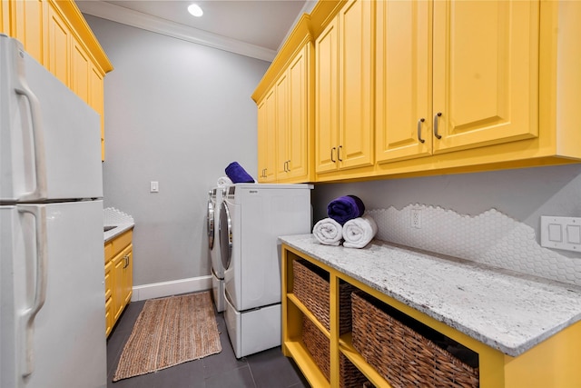 clothes washing area featuring dark tile patterned flooring, cabinets, washer and clothes dryer, and crown molding