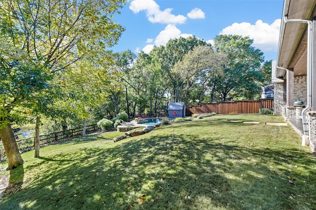 view of yard featuring a fenced in pool and a storage shed