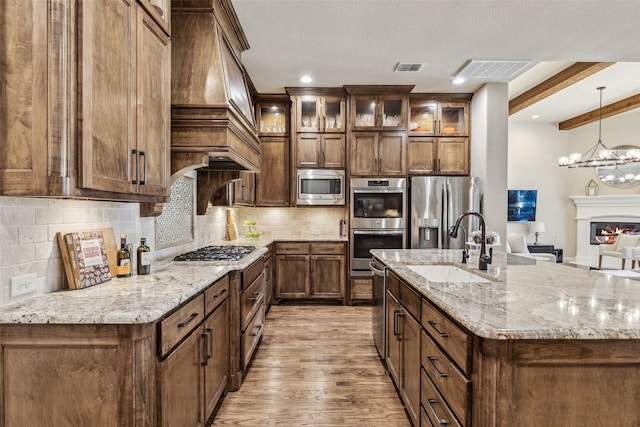 kitchen featuring visible vents, premium range hood, a sink, stainless steel appliances, and tasteful backsplash