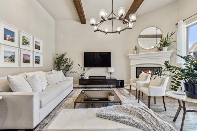 living room featuring wood finished floors, baseboards, an inviting chandelier, a glass covered fireplace, and beamed ceiling