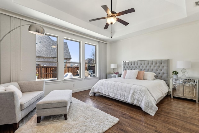 bedroom featuring ceiling fan, a tray ceiling, visible vents, and wood finished floors