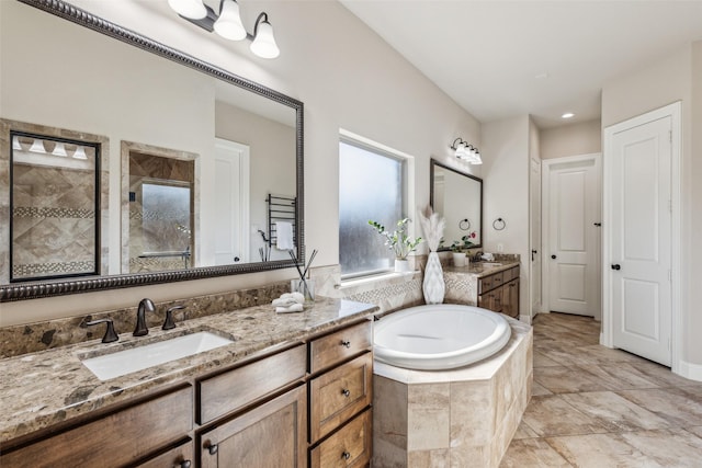 bathroom featuring a sink, tiled shower, a garden tub, and two vanities