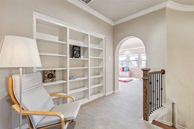 living area featuring baseboards, carpet floors, arched walkways, crown molding, and an upstairs landing