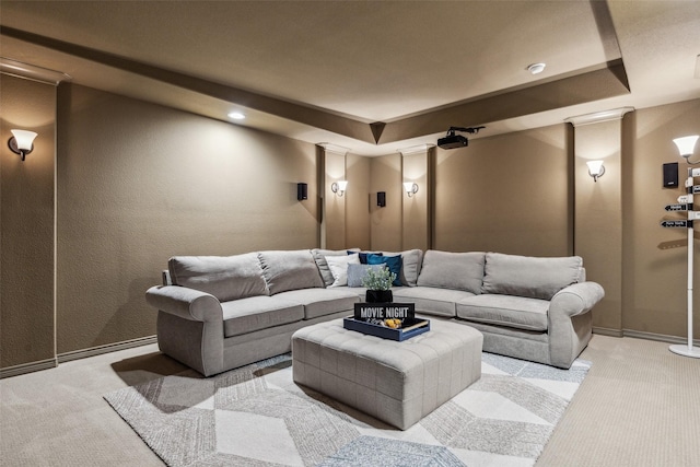 carpeted cinema with a raised ceiling, baseboards, and ornate columns