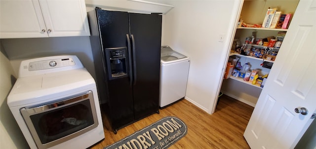 clothes washing area with separate washer and dryer, cabinets, and light hardwood / wood-style floors