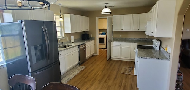 kitchen with white appliances, wood-type flooring, sink, decorative light fixtures, and white cabinetry