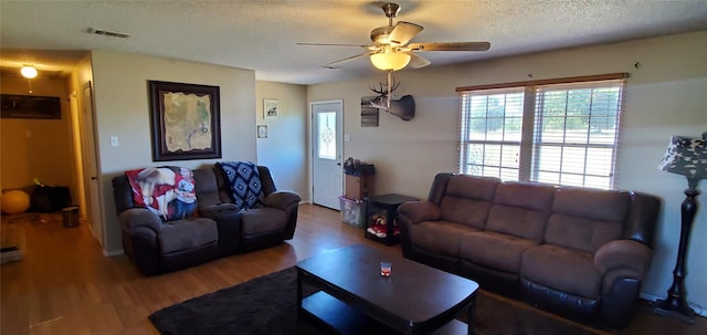 living room with a textured ceiling, hardwood / wood-style flooring, and ceiling fan