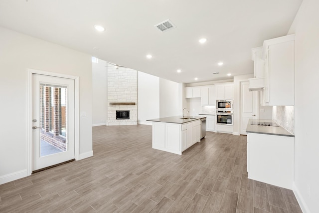 329 Sparkling Springs Dr, Waxahachie, TX 75165 - kitchen with a sink, open floor plan, stainless steel appliances, a stone fireplace, and light wood-type flooring