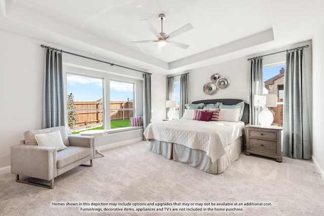 bedroom featuring multiple windows, light carpet, a raised ceiling, and ceiling fan