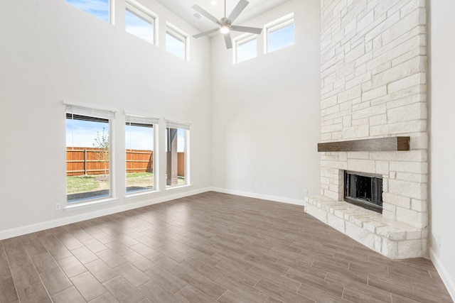 329 Sparkling Springs Dr, Waxahachie, TX 75165 - unfurnished living room featuring a ceiling fan, a high ceiling, wood finished floors, baseboards, and a stone fireplace