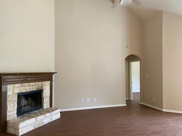 unfurnished living room featuring ceiling fan, dark hardwood / wood-style flooring, a fireplace, and high vaulted ceiling