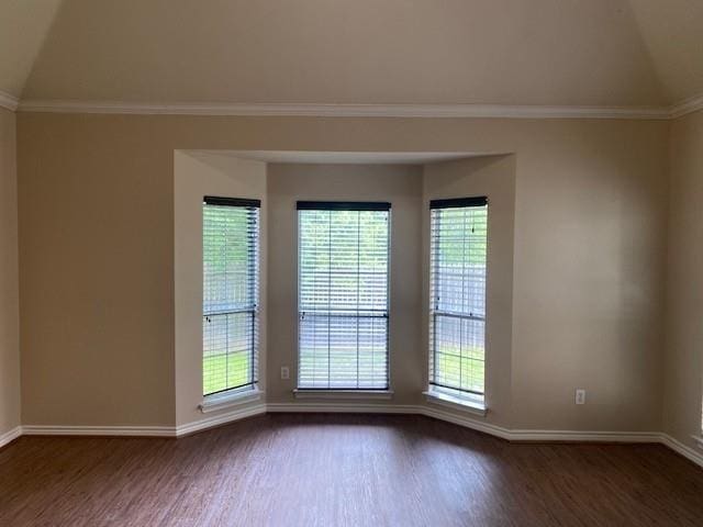 unfurnished room featuring dark hardwood / wood-style flooring, vaulted ceiling, and ornamental molding