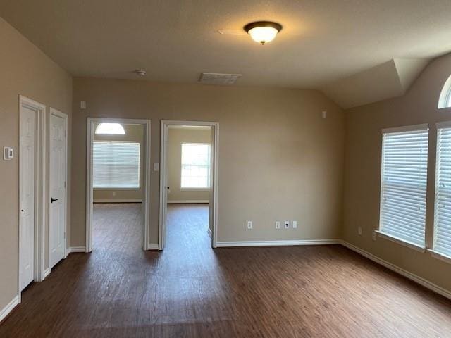 empty room with dark hardwood / wood-style floors and vaulted ceiling