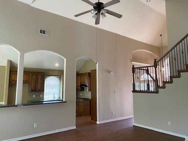 unfurnished living room featuring ceiling fan, dark hardwood / wood-style flooring, and a high ceiling