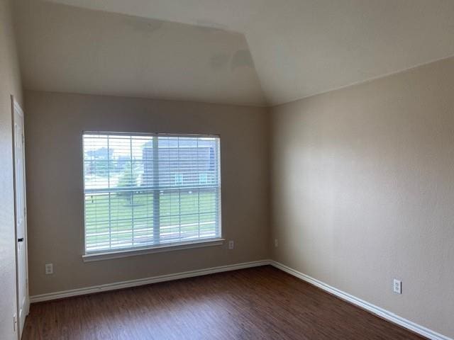 unfurnished room featuring dark hardwood / wood-style floors, lofted ceiling, and a wealth of natural light