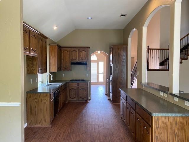 kitchen with lofted ceiling, sink, dark hardwood / wood-style floors, black dishwasher, and gas cooktop