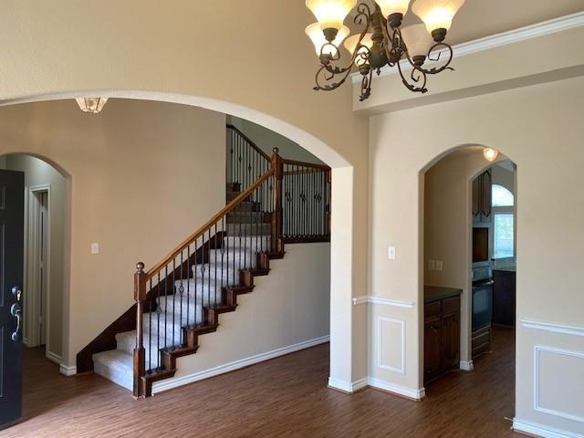 stairway featuring crown molding, a chandelier, and wood-type flooring