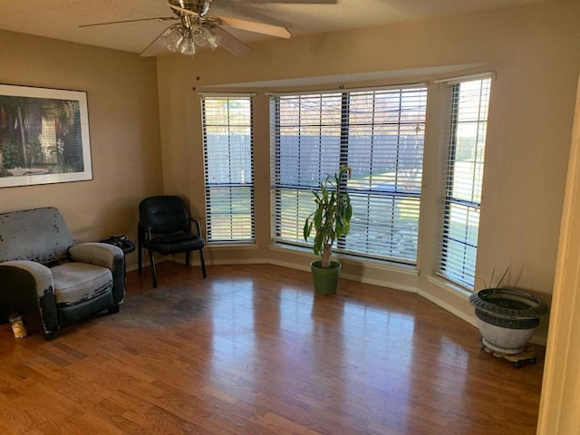 sitting room with ceiling fan, wood-type flooring, and a textured ceiling