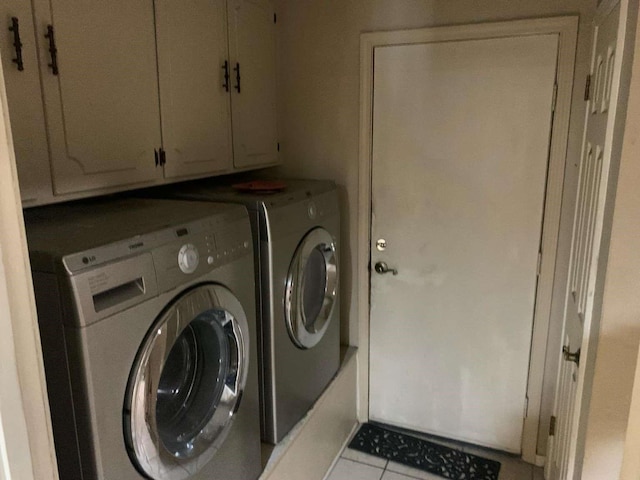 laundry room featuring light tile patterned flooring, cabinets, and separate washer and dryer