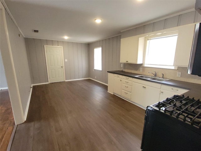 kitchen with black gas range, dark wood-type flooring, white cabinets, sink, and ornamental molding