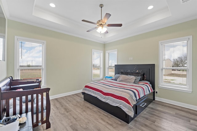 bedroom featuring hardwood / wood-style flooring, ceiling fan, a raised ceiling, and ornamental molding