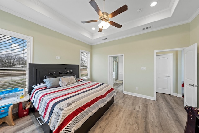 bedroom featuring a raised ceiling, ceiling fan, crown molding, and light wood-type flooring