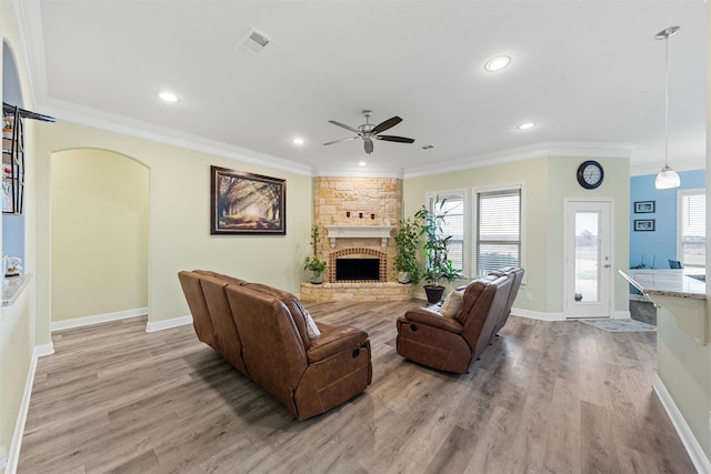 living room with ceiling fan, light hardwood / wood-style floors, crown molding, and a fireplace