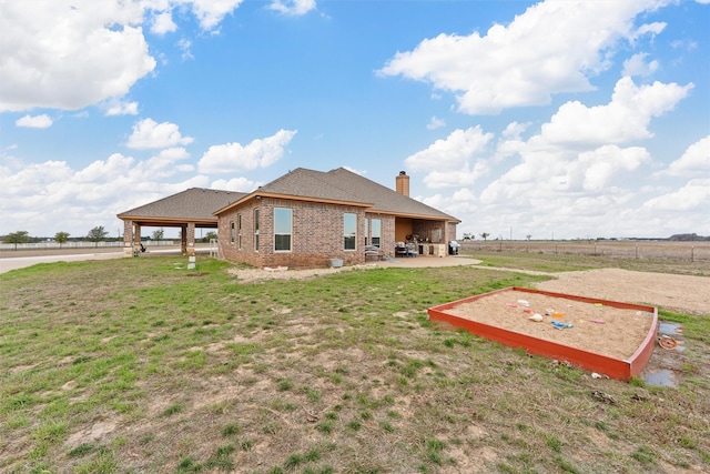 back of property featuring a lawn, a patio area, and a rural view