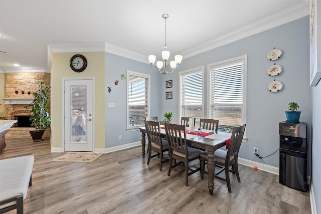 dining room with light hardwood / wood-style flooring, a fireplace, a wealth of natural light, and a chandelier