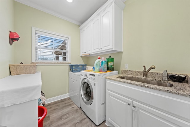 laundry area with sink, cabinets, light wood-type flooring, washer and dryer, and ornamental molding